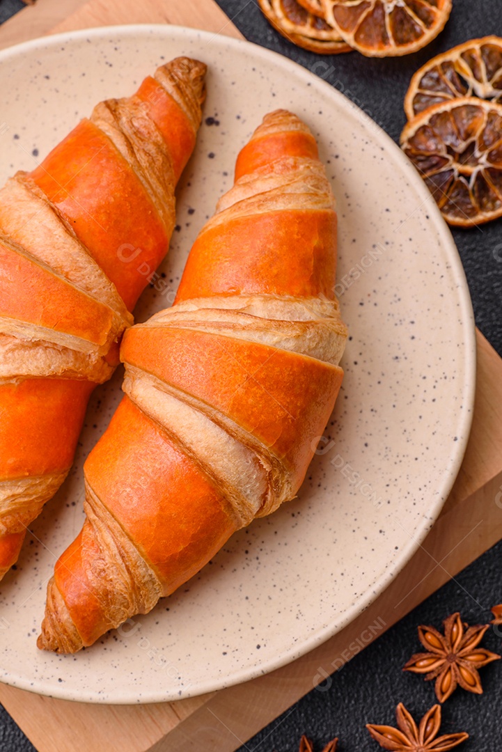 Deliciosos croissants franceses frescos e crocantes com recheio doce sobre fundo escuro de concreto