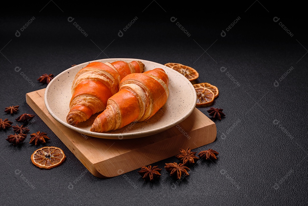 Deliciosos croissants franceses frescos e crocantes com recheio doce sobre fundo escuro de concreto