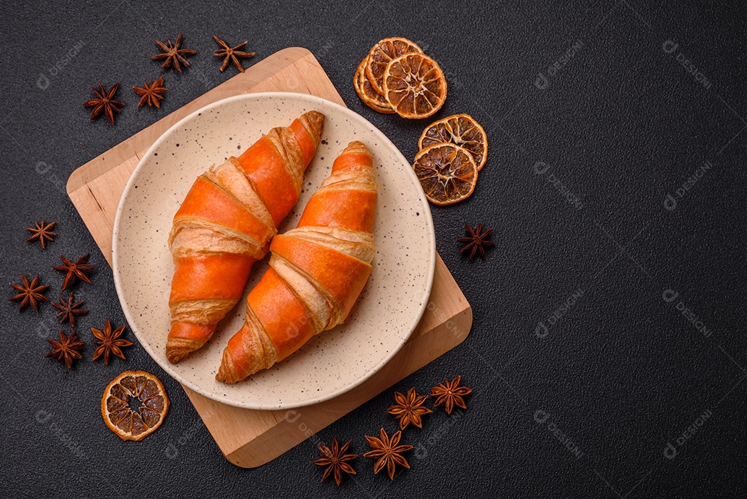 Deliciosos croissants franceses frescos e crocantes com recheio doce sobre fundo escuro de concreto
