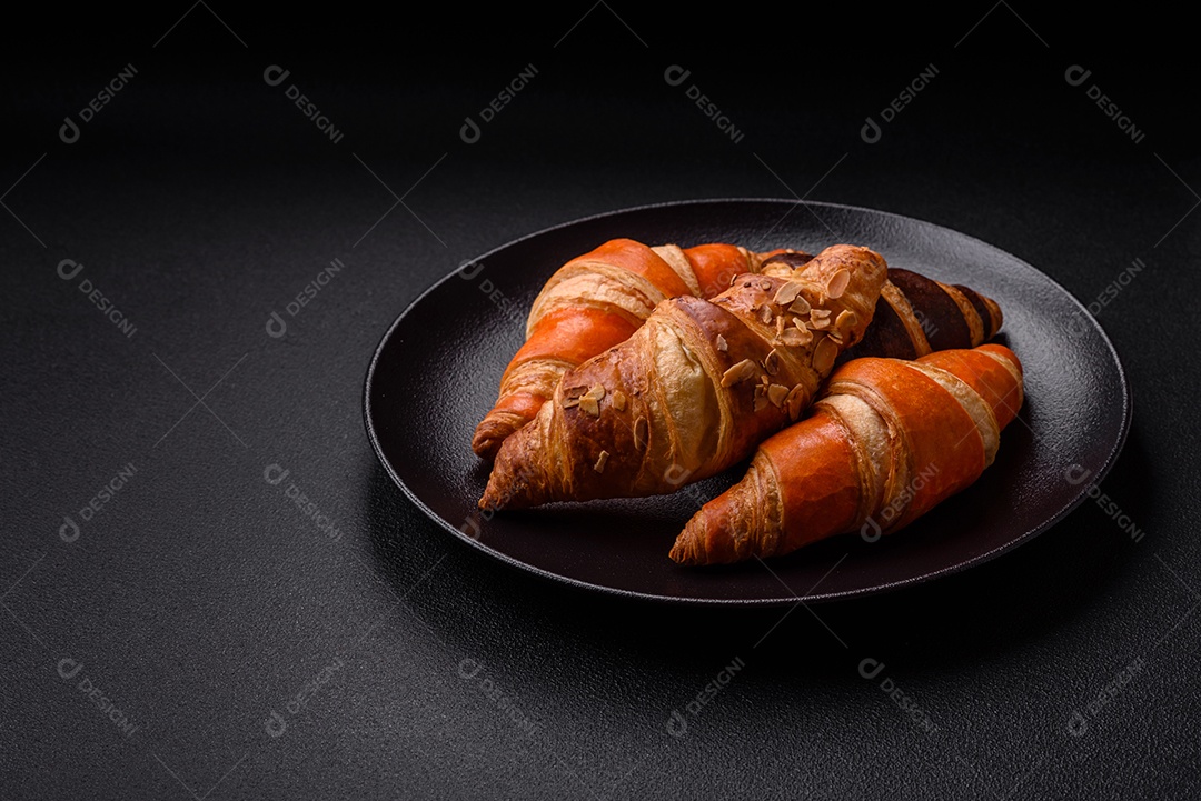 Deliciosos croissants franceses frescos e crocantes com recheio doce sobre fundo escuro de concreto