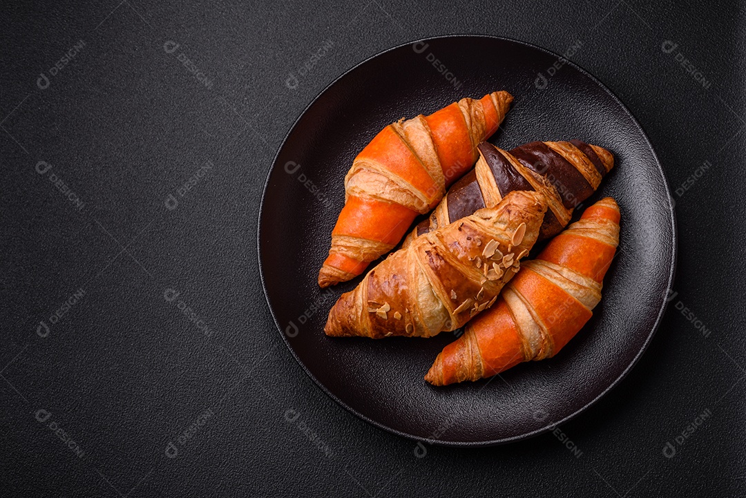 Deliciosos croissants franceses frescos e crocantes com recheio doce sobre fundo escuro de concreto