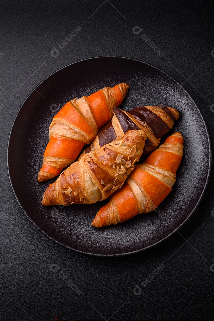 Deliciosos croissants franceses frescos e crocantes com recheio doce sobre fundo escuro de concreto