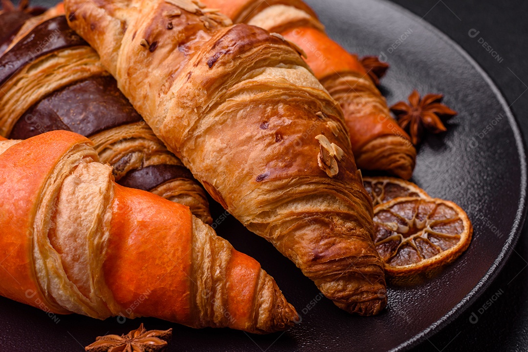Deliciosos croissants franceses frescos e crocantes com recheio doce sobre fundo escuro de concreto
