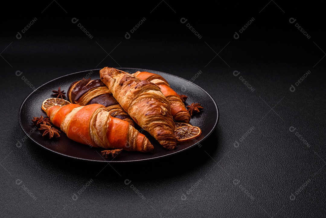 Deliciosos croissants franceses frescos e crocantes com recheio doce sobre fundo escuro de concreto