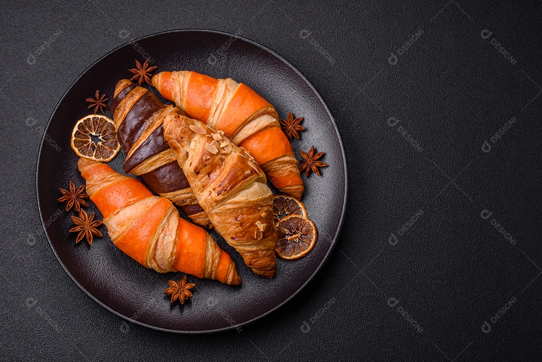 Deliciosos croissants franceses frescos e crocantes com recheio doce sobre fundo escuro de concreto