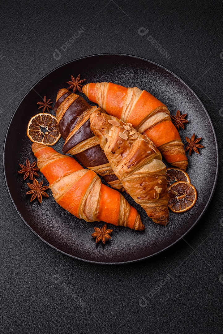 Deliciosos croissants franceses frescos e crocantes com recheio doce sobre fundo escuro de concreto