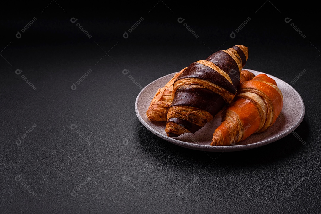 Deliciosos croissants franceses frescos e crocantes com recheio doce sobre fundo escuro de concreto