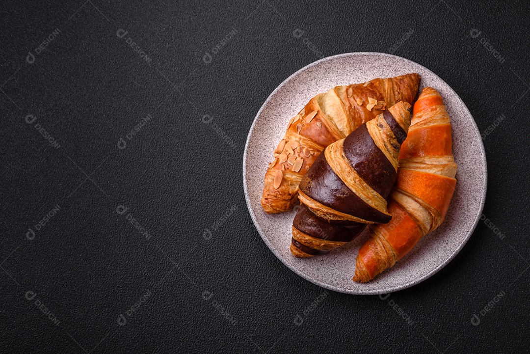 Deliciosos croissants franceses frescos e crocantes com recheio doce sobre fundo escuro de concreto