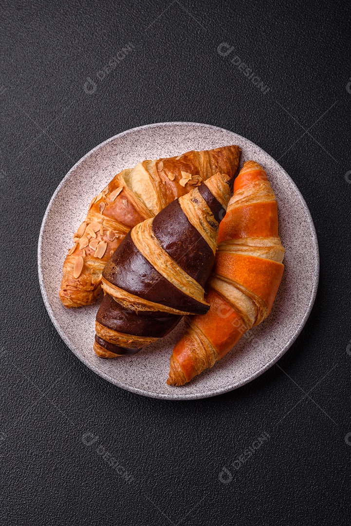 Deliciosos croissants franceses frescos e crocantes com recheio doce sobre fundo escuro de concreto