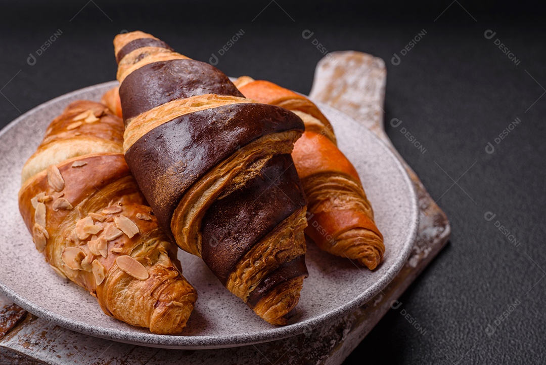 Deliciosos croissants franceses frescos e crocantes com recheio doce sobre fundo escuro de concreto
