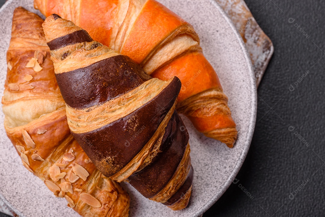 Deliciosos croissants franceses frescos e crocantes com recheio doce sobre fundo escuro de concreto