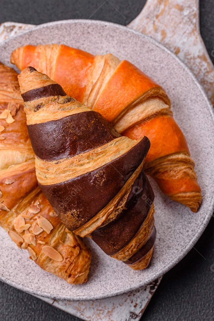 Deliciosos croissants franceses frescos e crocantes com recheio doce sobre fundo escuro de concreto