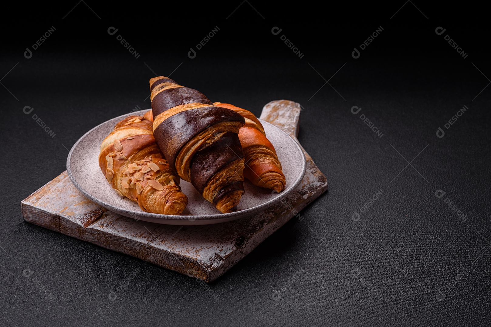 Deliciosos croissants franceses frescos e crocantes com recheio doce sobre fundo escuro de concreto