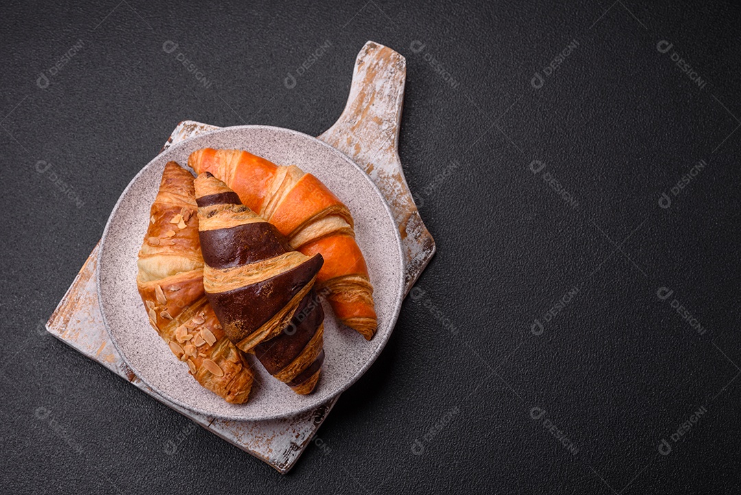 Deliciosos croissants franceses frescos e crocantes com recheio doce sobre fundo escuro de concreto