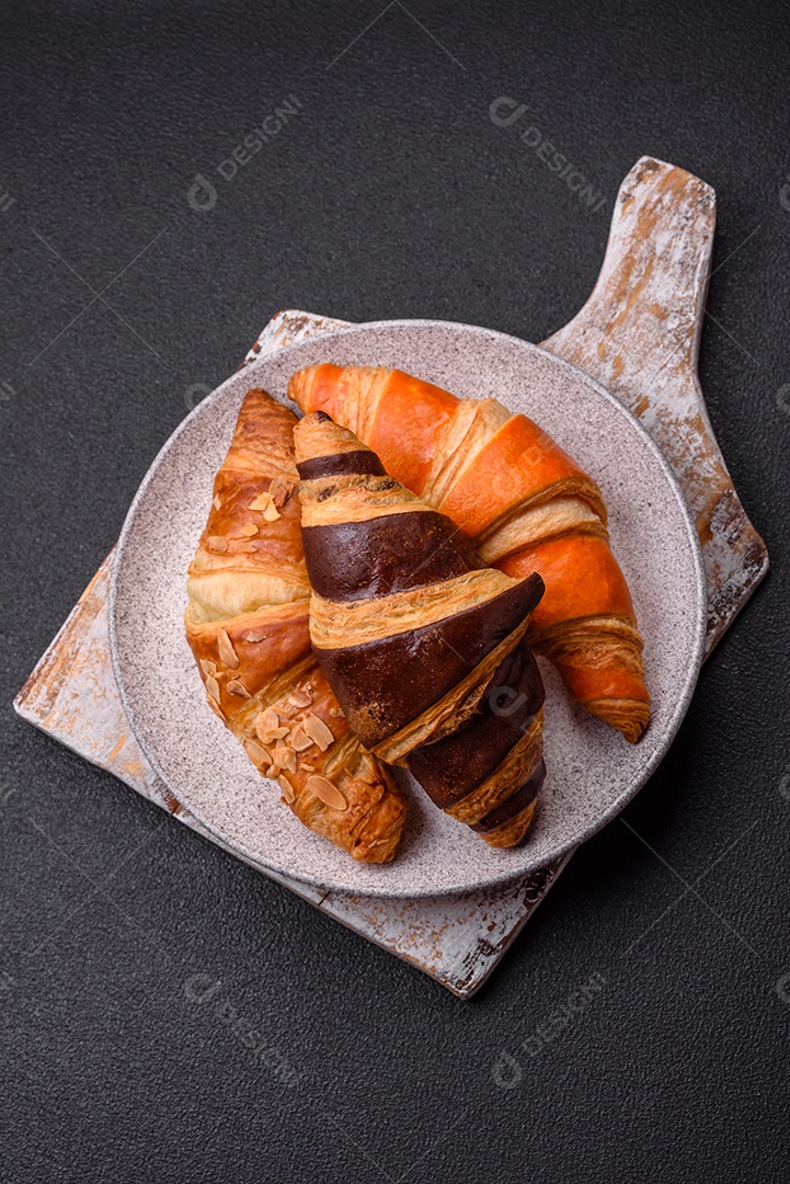 Deliciosos croissants franceses frescos e crocantes com recheio doce sobre fundo escuro de concreto