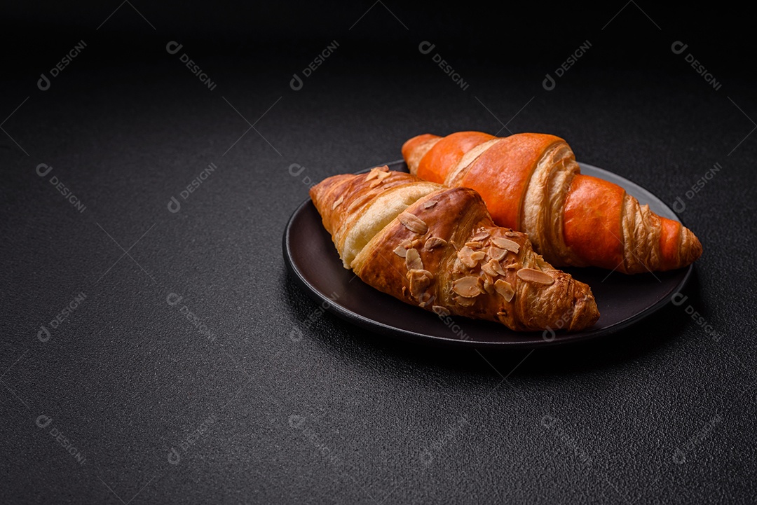 Deliciosos croissants franceses frescos e crocantes com recheio doce sobre fundo escuro de concreto