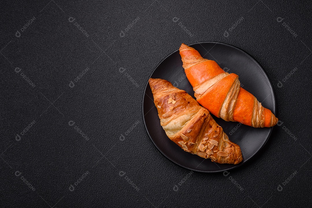 Deliciosos croissants franceses frescos e crocantes com recheio doce sobre fundo escuro de concreto