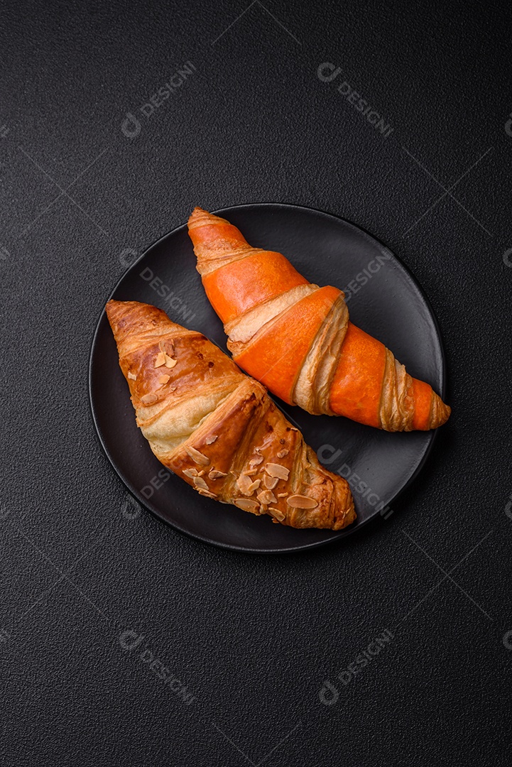 Deliciosos croissants franceses frescos e crocantes com recheio doce sobre fundo escuro de concreto