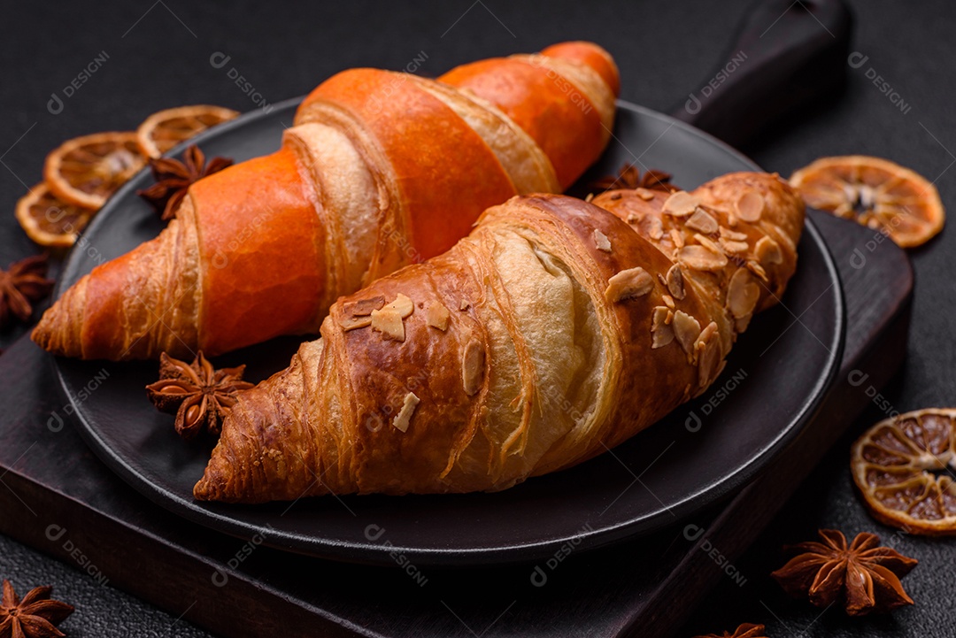 Deliciosos croissants franceses frescos e crocantes com recheio doce sobre fundo escuro de concreto