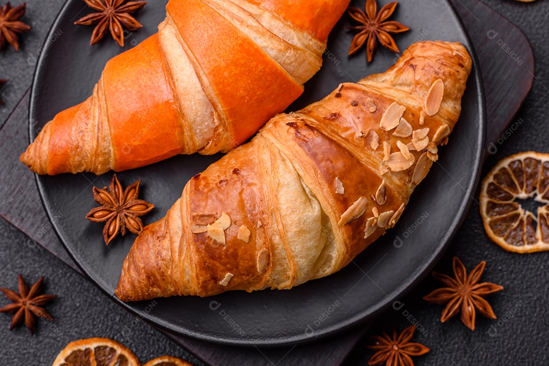 Deliciosos croissants franceses frescos e crocantes com recheio doce sobre fundo escuro de concreto