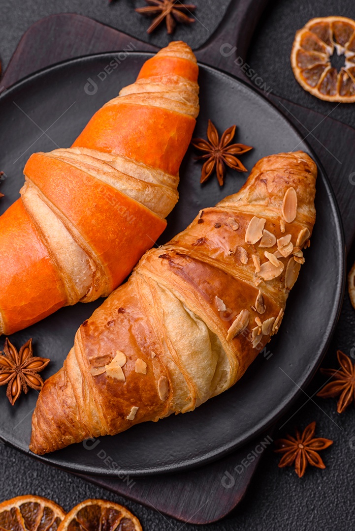 Deliciosos croissants franceses frescos e crocantes com recheio doce sobre fundo escuro de concreto