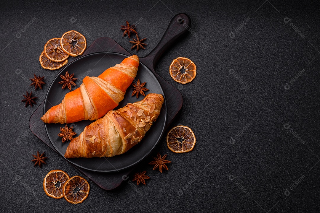 Deliciosos croissants franceses frescos e crocantes com recheio doce sobre fundo escuro de concreto