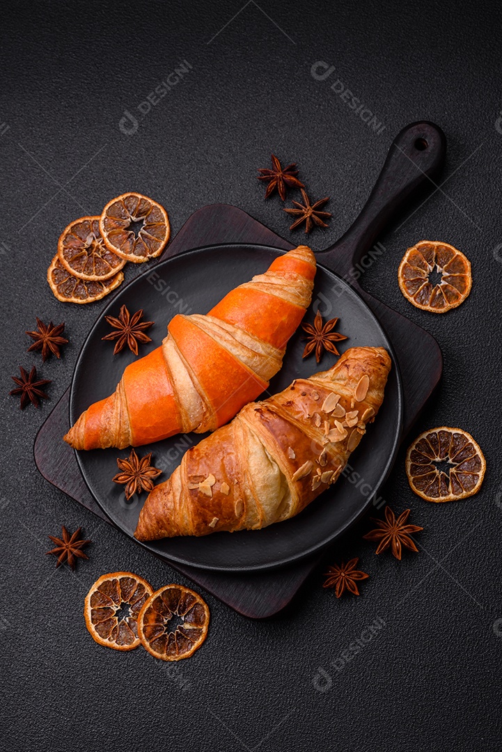 Deliciosos croissants franceses frescos e crocantes com recheio doce sobre fundo escuro de concreto