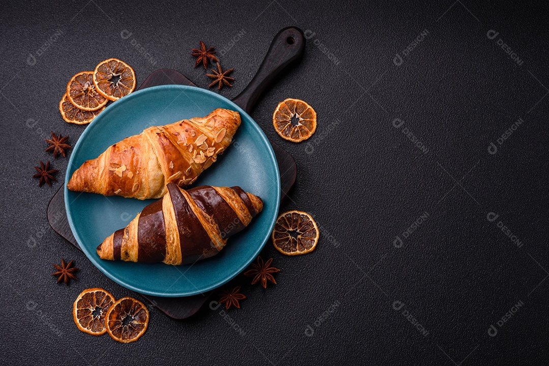 Deliciosos croissants franceses frescos e crocantes com recheio doce sobre fundo escuro de concreto