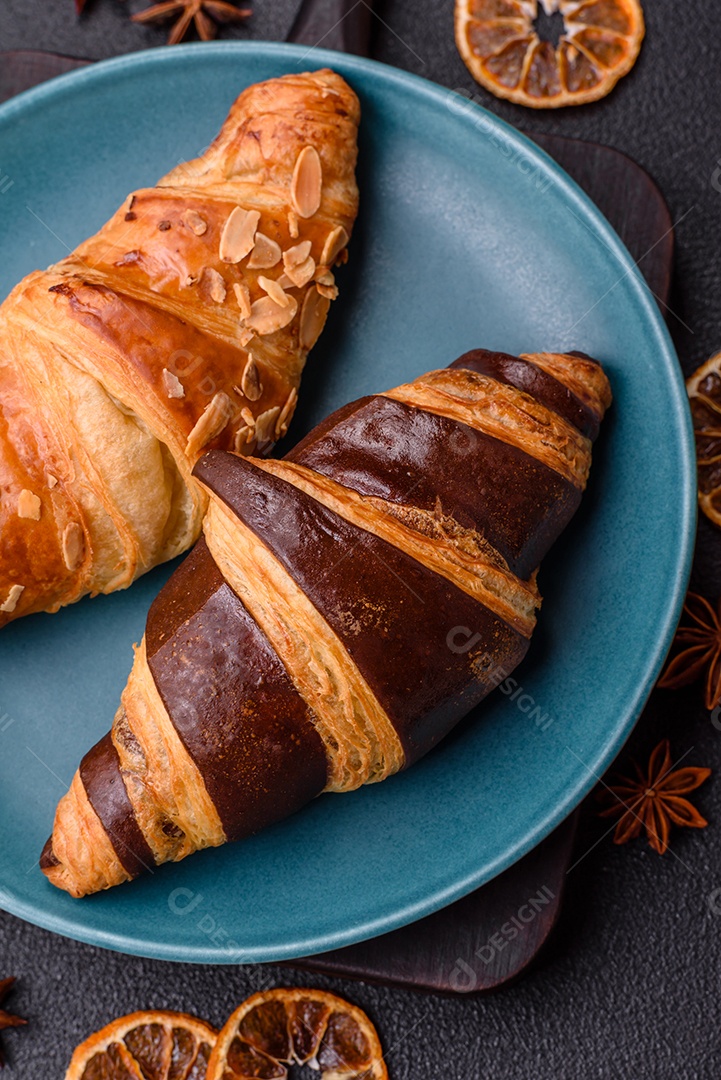 Deliciosos croissants franceses frescos e crocantes com recheio doce sobre fundo escuro de concreto
