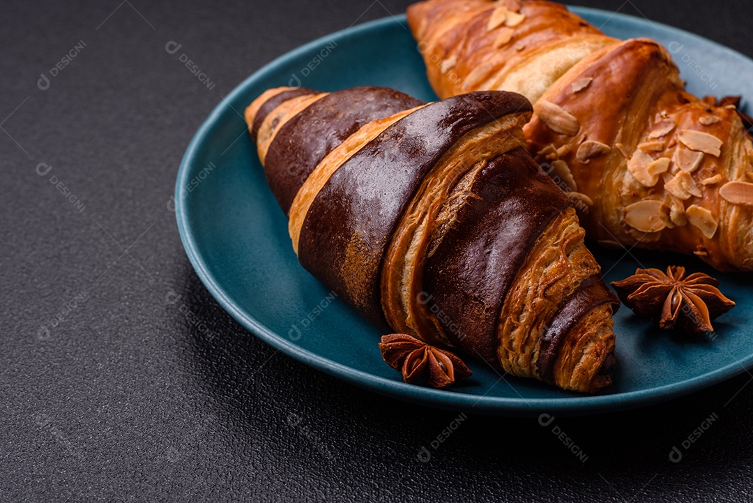Deliciosos croissants franceses frescos e crocantes com recheio doce sobre fundo escuro de concreto