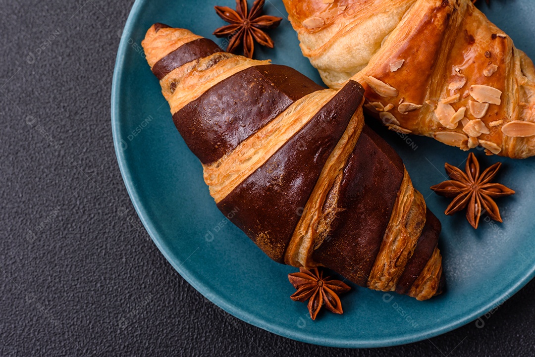 Deliciosos croissants franceses frescos e crocantes com recheio doce sobre fundo escuro de concreto