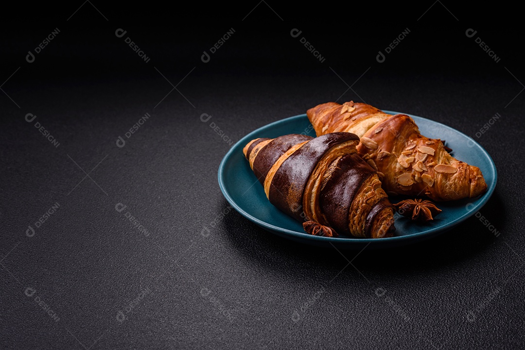 Deliciosos croissants franceses frescos e crocantes com recheio doce sobre fundo escuro de concreto