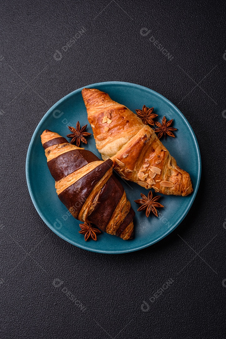 Deliciosos croissants franceses frescos e crocantes com recheio doce sobre fundo escuro de concreto