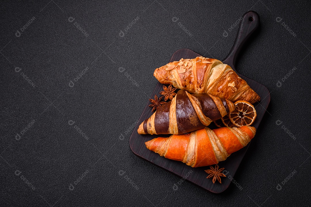 Deliciosos croissants franceses frescos e crocantes com recheio doce sobre fundo escuro de concreto
