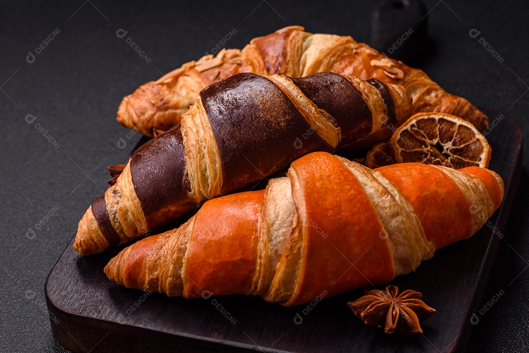 Deliciosos croissants franceses frescos e crocantes com recheio doce sobre fundo escuro de concreto