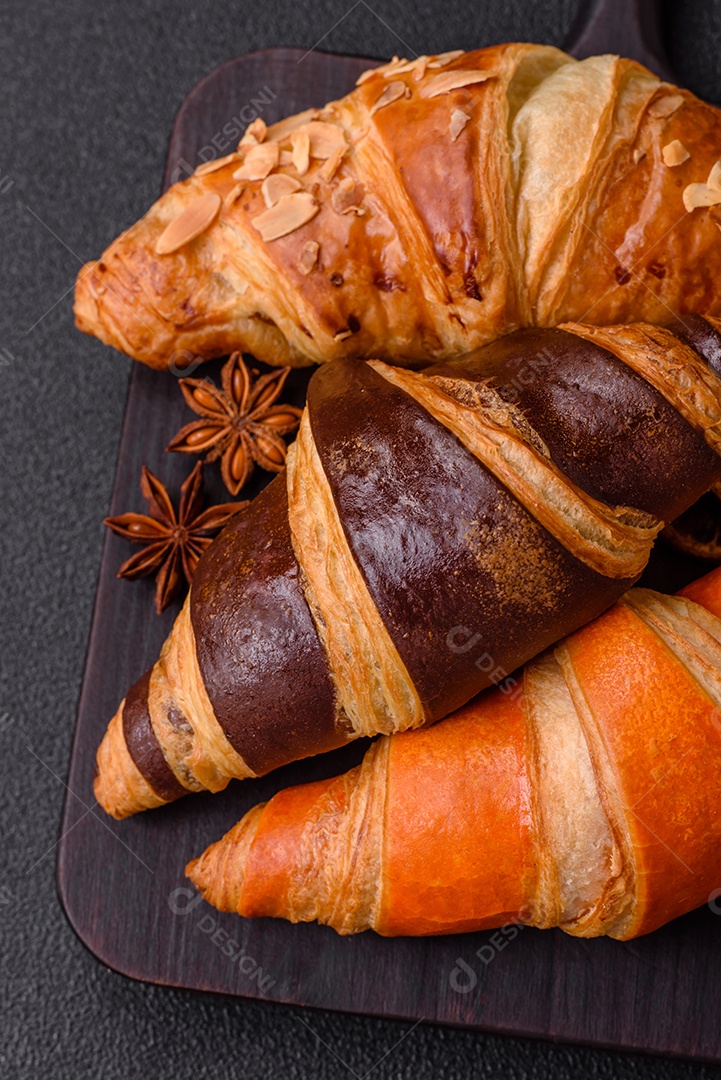 Deliciosos croissants franceses frescos e crocantes com recheio doce sobre fundo escuro de concreto