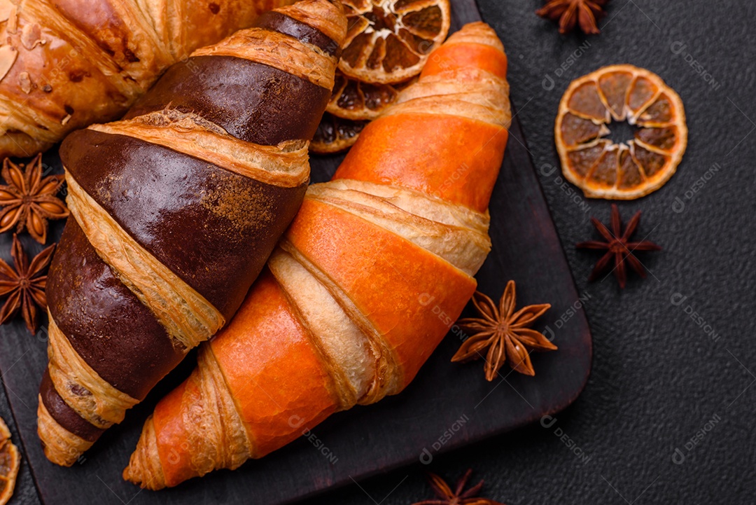 Deliciosos croissants franceses frescos e crocantes com recheio doce sobre fundo escuro de concreto