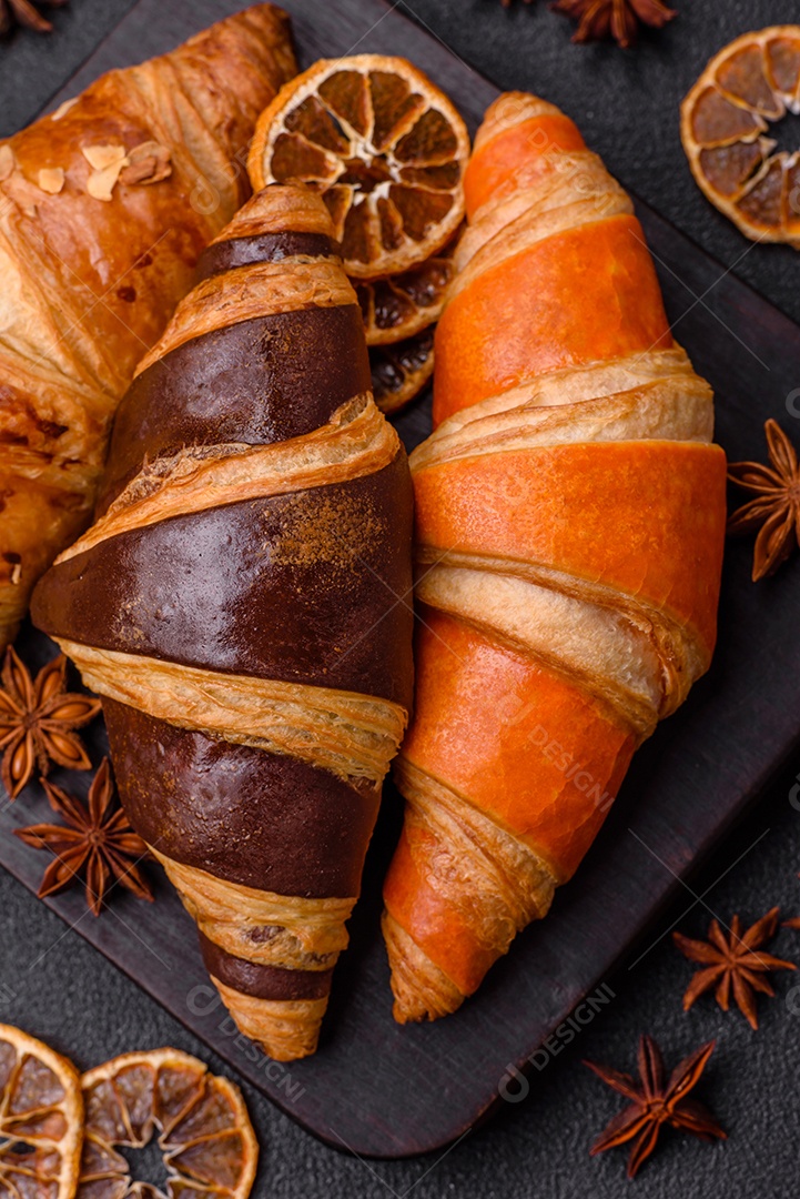 Deliciosos croissants franceses frescos e crocantes com recheio doce sobre fundo escuro de concreto