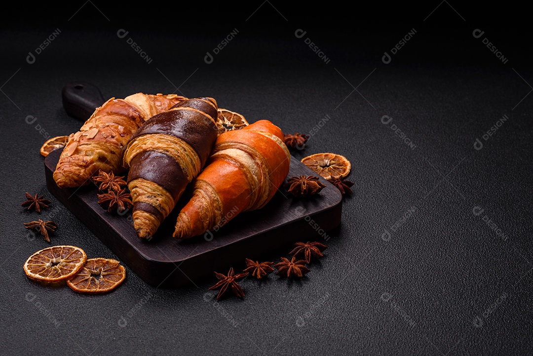 Deliciosos croissants franceses frescos e crocantes com recheio doce sobre fundo escuro de concreto