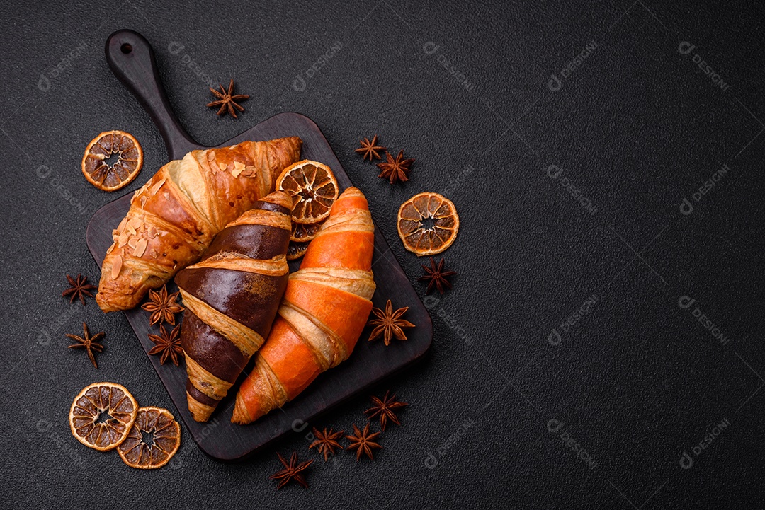 Deliciosos croissants franceses frescos e crocantes com recheio doce sobre fundo escuro de concreto