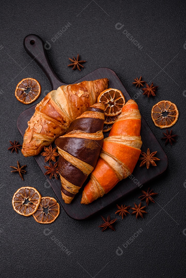 Deliciosos croissants franceses frescos e crocantes com recheio doce sobre fundo escuro de concreto