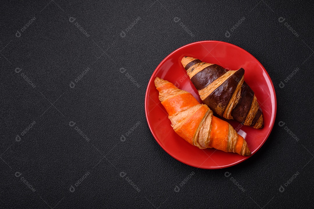 Deliciosos croissants franceses frescos e crocantes com recheio doce sobre fundo escuro de concreto