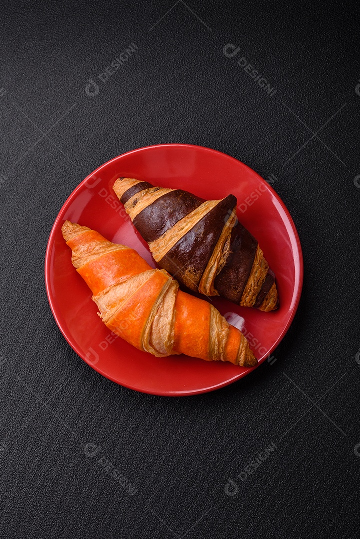 Deliciosos croissants franceses frescos e crocantes com recheio doce sobre fundo escuro de concreto