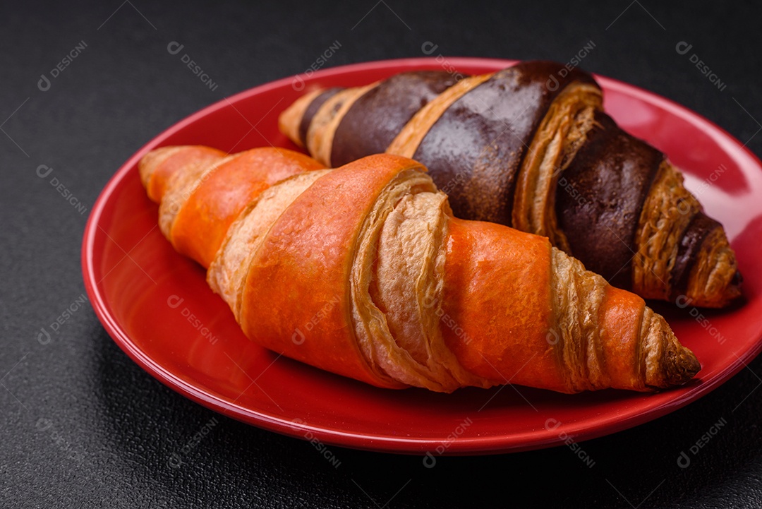 Deliciosos croissants franceses frescos e crocantes com recheio doce sobre fundo escuro de concreto