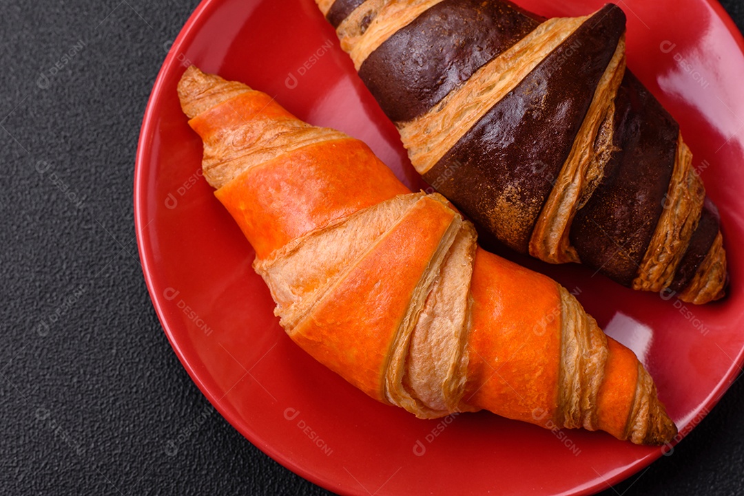 Deliciosos croissants franceses frescos e crocantes com recheio doce sobre fundo escuro de concreto