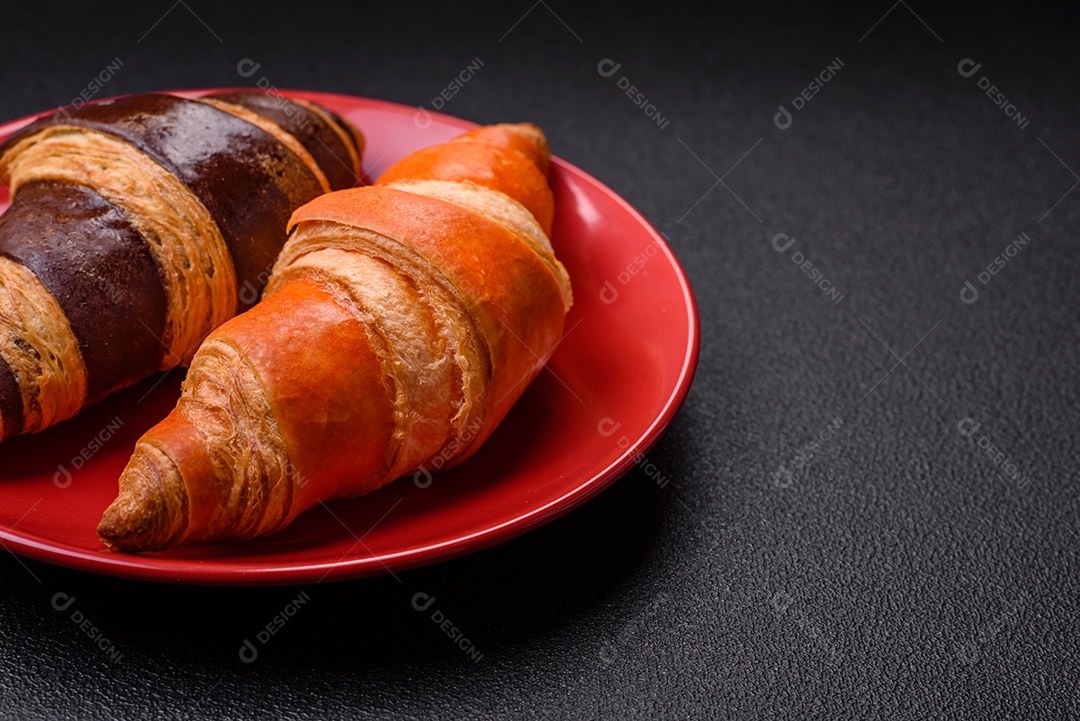 Deliciosos croissants franceses frescos e crocantes com recheio doce sobre fundo escuro de concreto