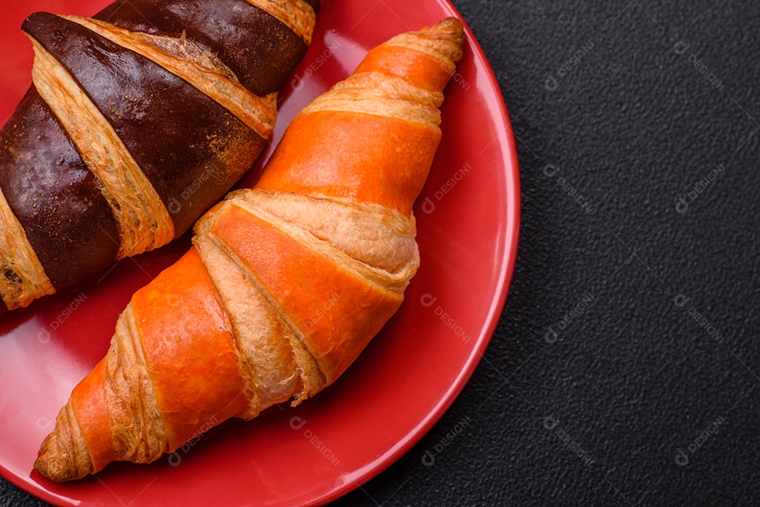 Deliciosos croissants franceses frescos e crocantes com recheio doce sobre fundo escuro de concreto