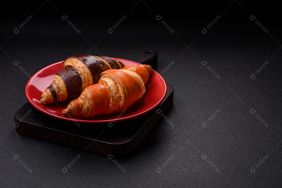 Deliciosos croissants franceses frescos e crocantes com recheio doce sobre fundo escuro de concreto