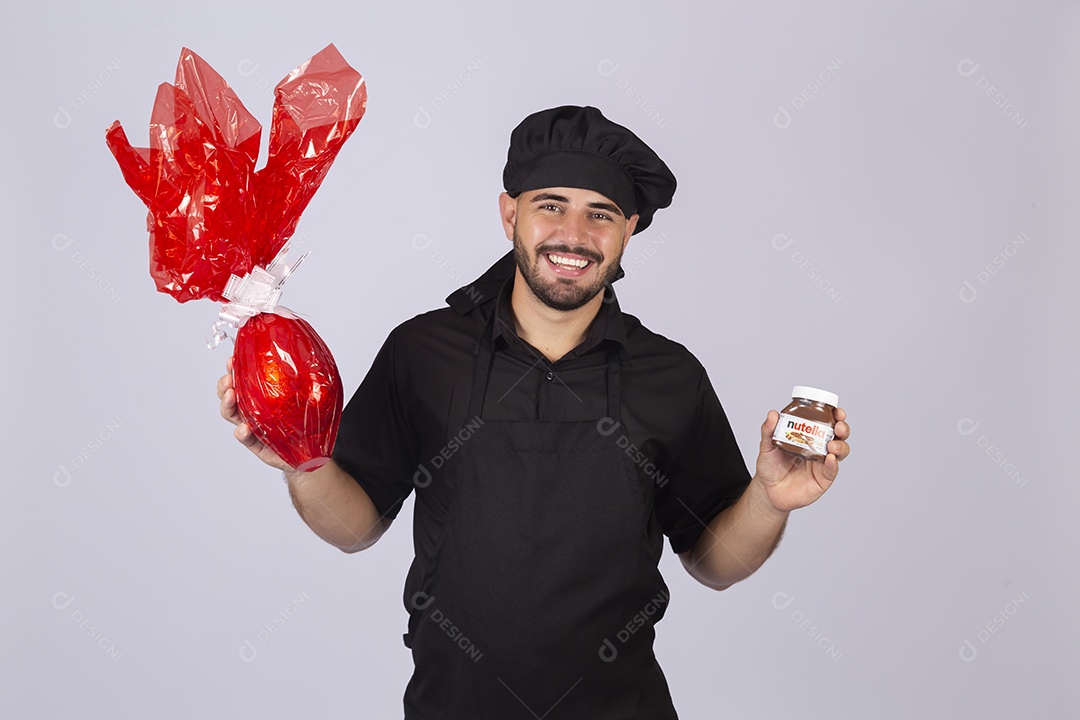 Homem jovem cozinheiro sobre fundo isolado segurando ovos de páscoa