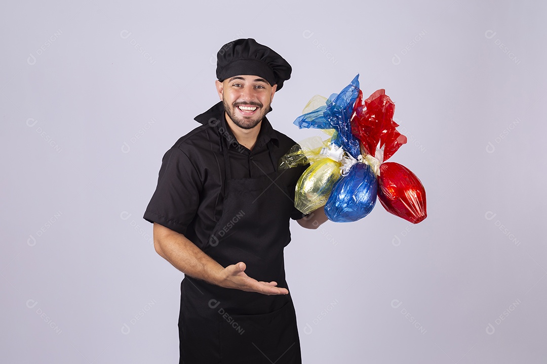 Homem jovem cozinheiro sobre fundo isolado segurando ovos de páscoa
